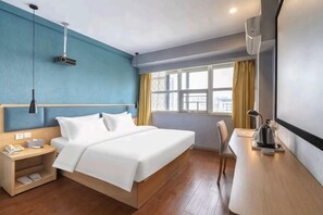 Une chambre d’hôtel avec un lit, une table de chevet, une lampe et une fenêtre avec des rideaux.