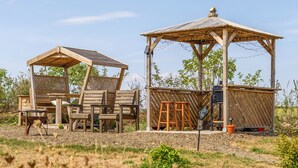 A rustic wooden structure with a covered seating area and a separate open pavilion. - Cosy Luxury Owls Roost Hut With Private Hot Tub (Umberleigh)