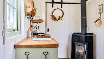 A kitchen with a wooden countertop, a sink, a stove, and a window.