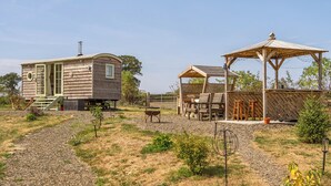 A wooden cabin with a small porch and a covered seating area. - Cosy Luxury Owls Roost Hut With Private Hot Tub (Umberleigh)