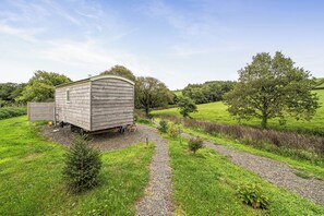 A wooden mobile home with a gravel driveway and a small garden area.