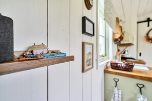 A kitchen with wooden shelves, a small model house, and various framed pictures on the wall.