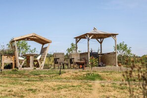 A rustic outdoor seating area with wooden structures and chairs. - Cosy Luxury Foxglove Hut With Private Fire Bowl (Umberleigh)