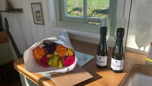 Un comptoir de cuisine orné d’un bouquet de roses aux couleurs vives, deux bouteilles de vin Prosecco et une fenêtre donnant sur un champ verdoyant.