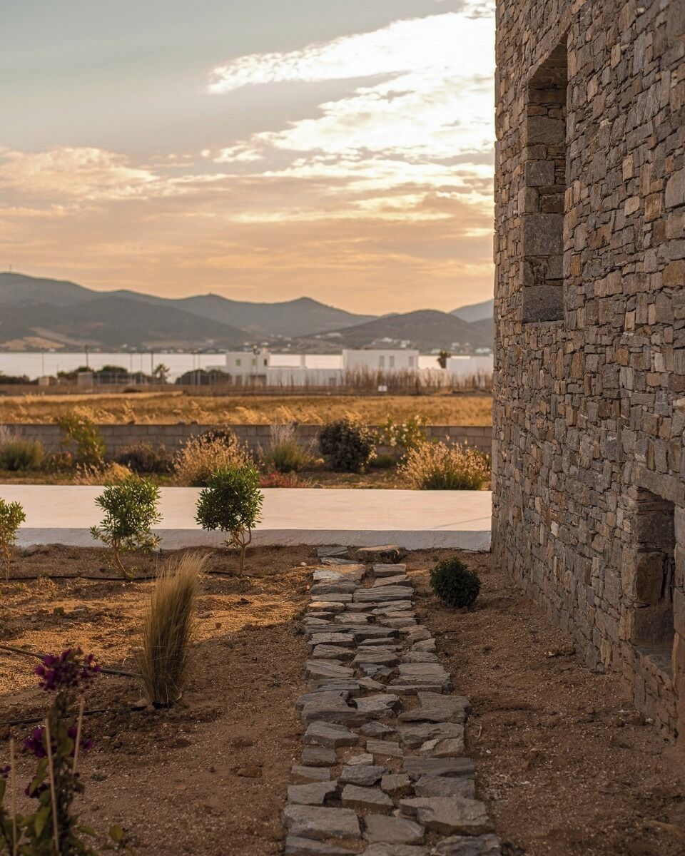 A stone building with a stone pathway leading to a white building in the background.