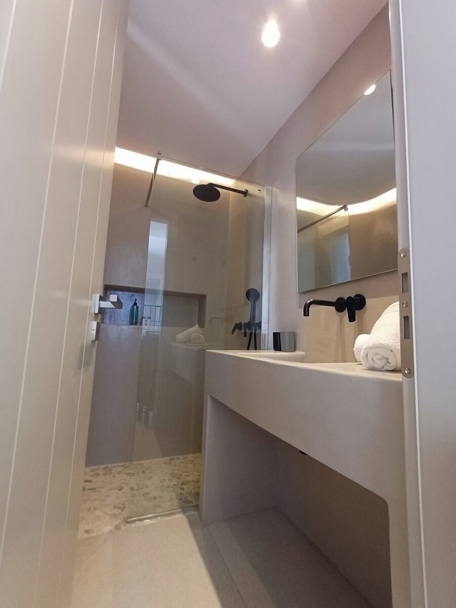 A modern bathroom with a glass shower enclosure, a white sink, and a mirror.