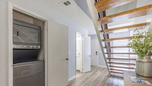 Eine Küche mit Backofen, einer Holztreppe und Blick auf einen Flur.