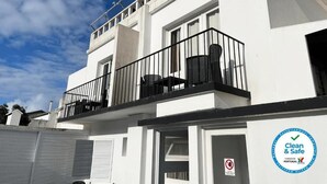 Un edificio blanco con un balcón, un letrero que dice 'Clean & Safe' y un letrero de prohibido fumar.