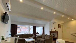 Una sala de estar con un sofá, una mesita, una chimenea y un televisor montado en la pared.