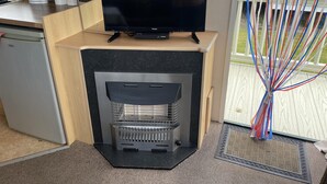 Una cocina moderna con televisión integrada, un refrigerador compacto y una chimenea.