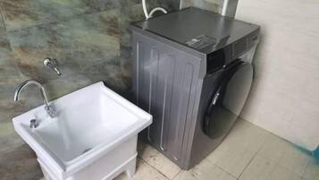 Un baño pequeño con lavamanos, lavadora y espejo.