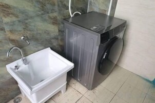 Un baño pequeño con lavamanos, lavadora y espejo.