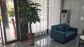 A modern lobby with a potted plant, a blue sofa, and a marble floor.