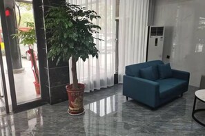 A modern lobby with a potted plant, a blue sofa, and a marble floor. - Urban Garden Hotel (Daye Yurun) (Daye)