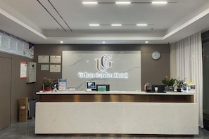 A reception desk with a logo, a clock, and framed certificates on the wall. - Urban Garden Hotel (Daye Yurun) (Daye)