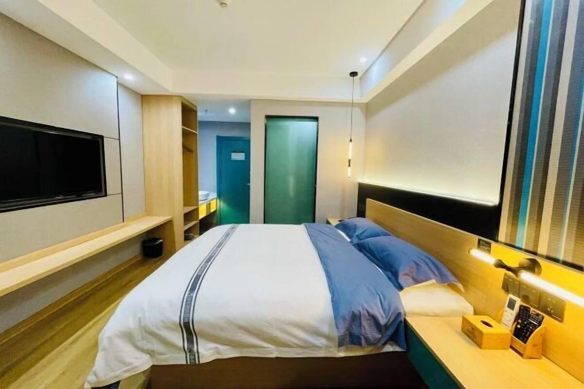 Una habitación de hotel moderna con cama, mesita de noche, televisión y una puerta que da a otra habitación.