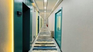 Un couloir d’hôtel avec un tapis à rayures, des portes des deux côtés et un panneau indiquant le numéro de chambre 8210.