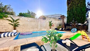 A pool area with lounge chairs, a small inflatable pool, and a slide.