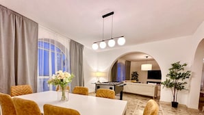 A dining area with a white table and yellow chairs, a flower vase, and a foosball table in the background.
