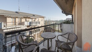 A balcony with wicker furniture, a view of neighboring buildings, and a clear sky. - Apt24 - The Roof in Desenzano del Garda (Desenzano del Garda)