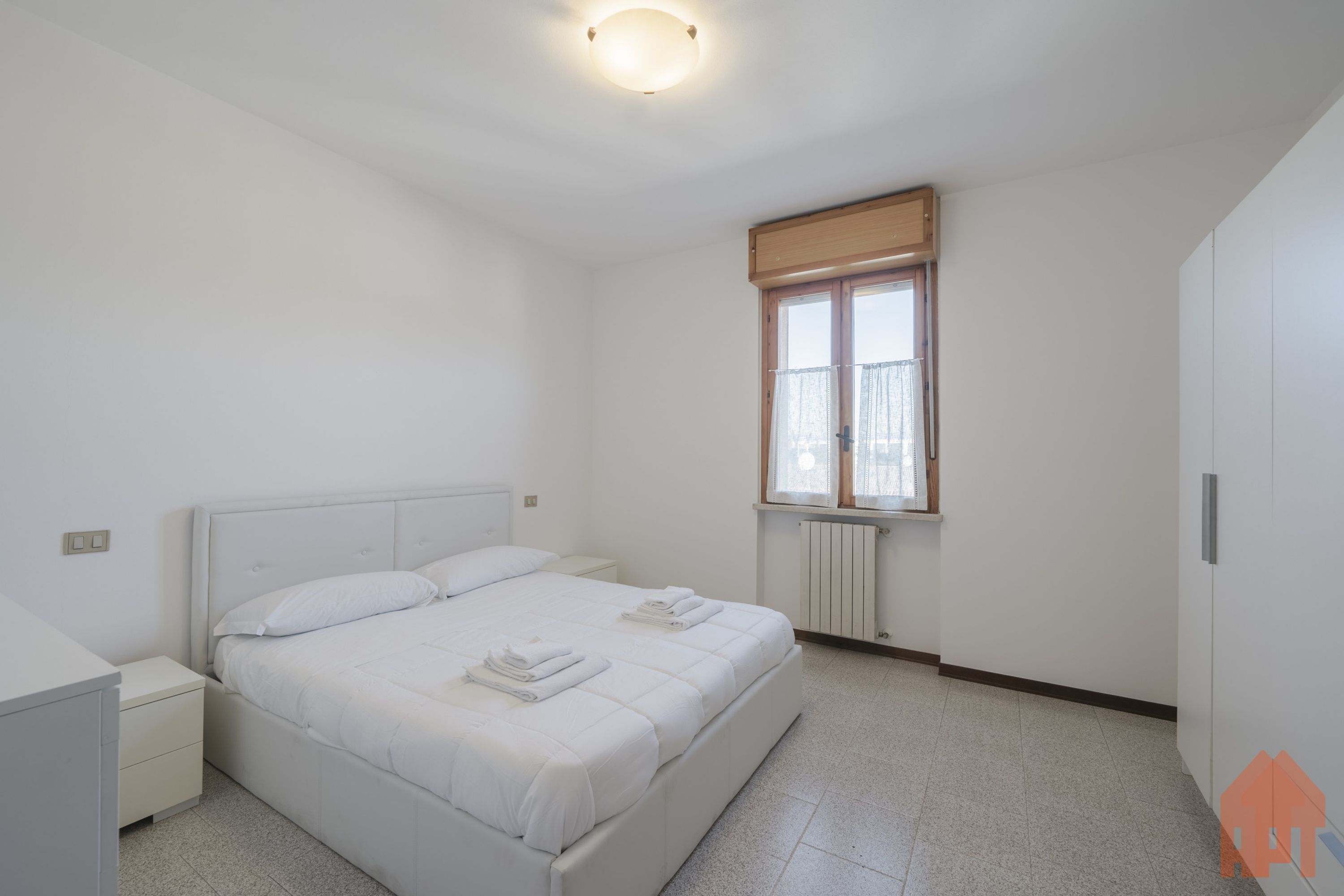 Ein Schlafzimmer mit Bett, Nachttisch und Fenster.