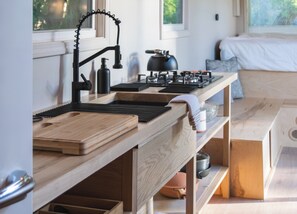 Une cuisine moderne avec des plans de travail en bois, un robinet noir et une bouilloire.