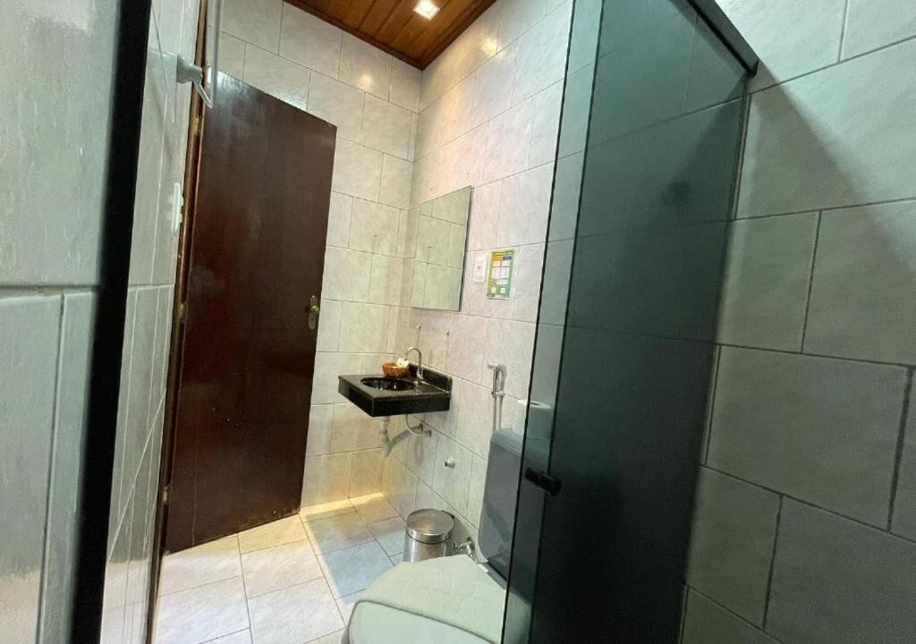 Une salle de bain comprenant des toilettes, un lavabo et une douche à parois de verre.