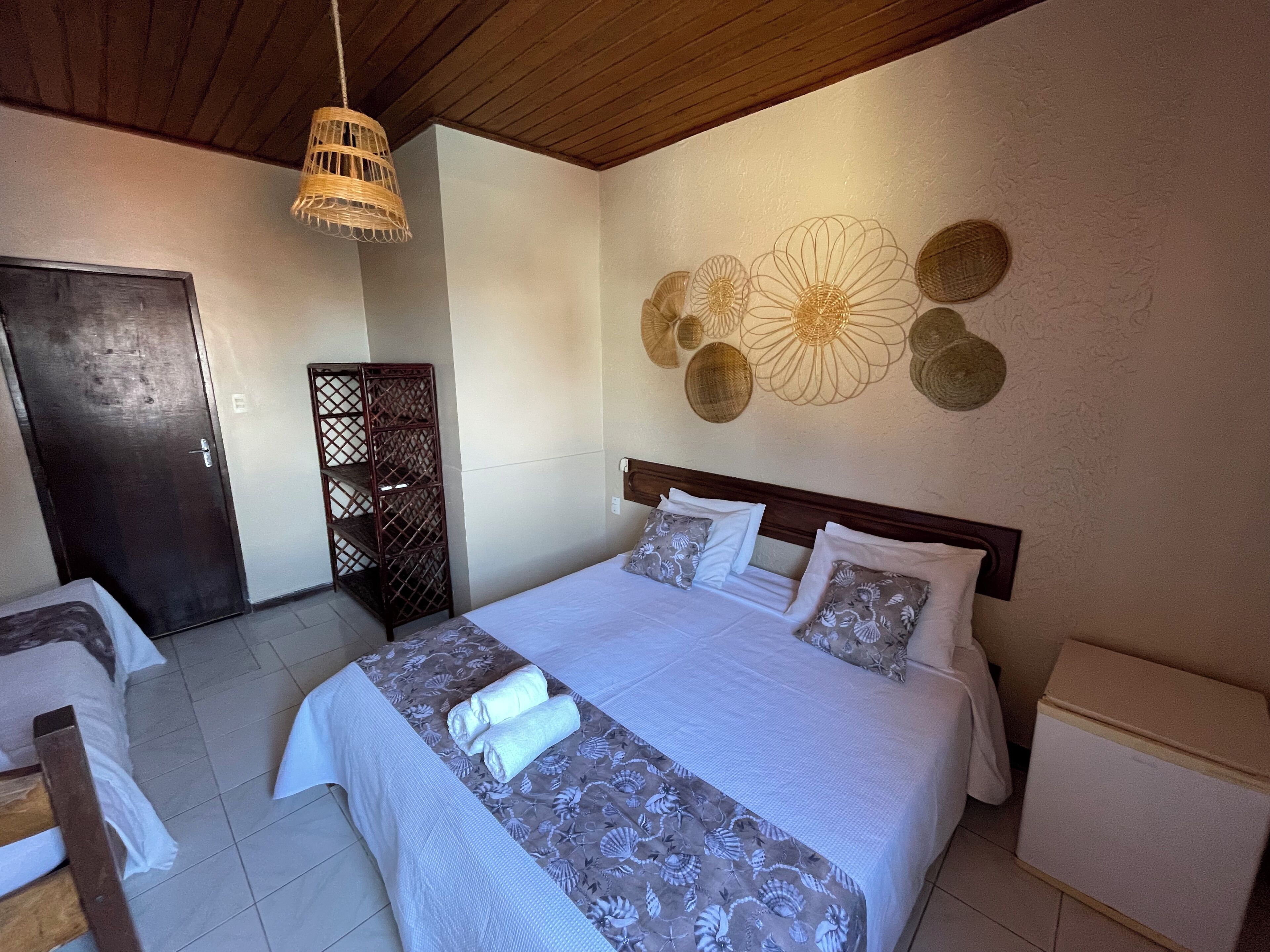 Un dormitorio ordenado con cama, mesitas de noche, un armario y un elemento decorativo en la pared.