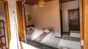 A bedroom with a bed, a hanging light fixture, and a view of another room. - Pousada Estevão (Cairu)