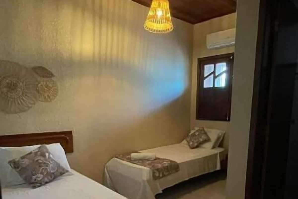 Une chambre avec deux lits simples, un plafond en bois et un luminaire suspendu.