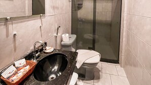 A bathroom with a black sink, a toilet, and a glass-enclosed shower. - Pousada Estevão (Cairu)
