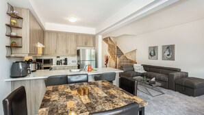 Un appartement moderne comprenant une cuisine, un coin repas, un salon et un escalier.