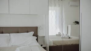 Ein Hotelzimmer mit Bett, Nachttisch, Spiegel und einem Fenster mit Vorhängen.