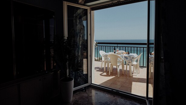 Ein Balkon mit Tisch und Stühlen mit Blick auf das Meer.