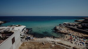 Blick auf die Küste mit Strand, felsigem Ufer und Gebäuden.