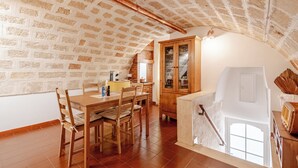 Eine rustikale Küche mit freiliegenden Backsteinwänden, Holzschränken und einem Essbereich mit Tisch und Stühlen.