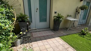 A building entrance with a double door, a small outdoor seating area, and potted plants.