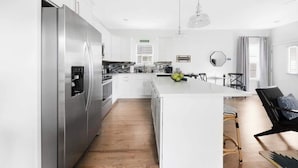 Una cocina moderna con electrodomésticos de acero inoxidable, una isla central y un comedor con una silla y una mesa.