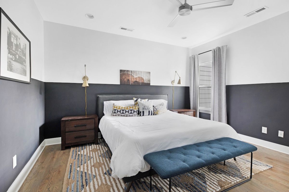 A bedroom with a bed, bedside tables, a bench, a floor lamp, and a ceiling fan.