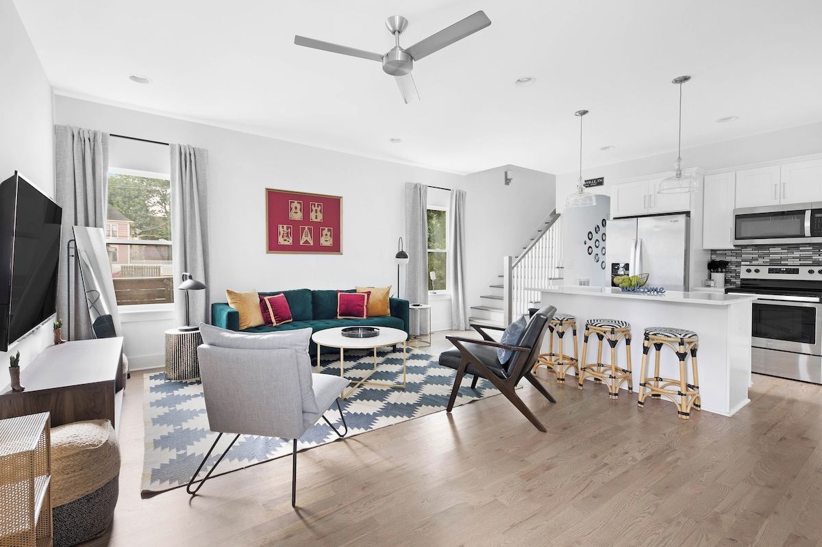 Vibrant teal velvet sofa and patterned geometric area rug anchoring a bright, welcoming living room layout.