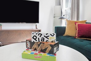 A living room with a flat-screen TV, a coffee table, and a sofa with cushions.