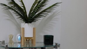 A glass shelf with a potted plant, a framed picture, and various items including a perfume bottle and a small vase. - Luxurious 2 Beds Flat in Mayfair on Oxford Street (London)