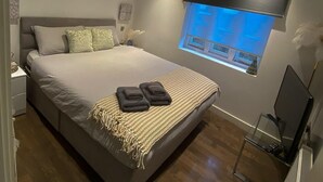 A modern bedroom with a large bed, a window with a view, and a desk with a computer. - Luxurious 2 Beds Flat in Mayfair on Oxford Street (London)