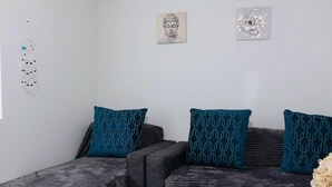 A modern living room with a sectional sofa, patterned cushions, a glass coffee table, and wall art. - Luxurious 2 Beds Flat in Mayfair on Oxford Street (London)