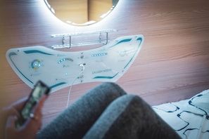 Una habitación moderna con un diseño de techo único, un dispositivo montado y una cama con ropa de cama estampada.