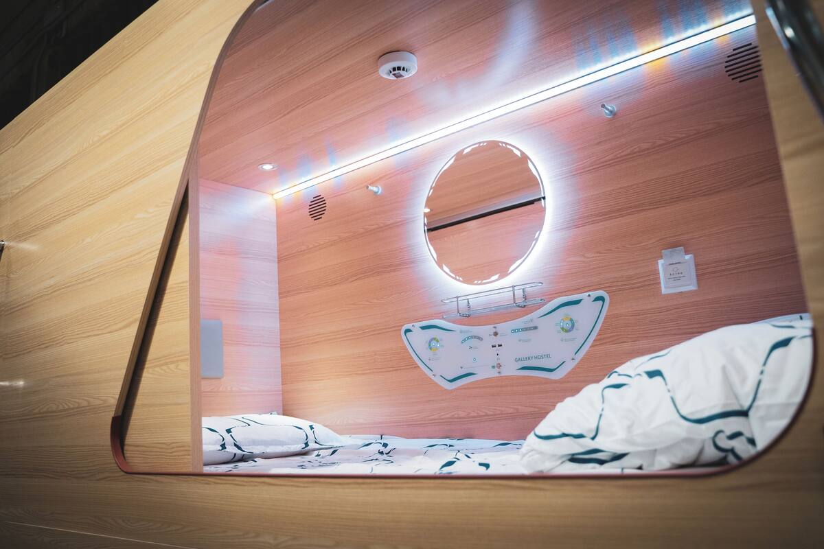 Une pièce moderne aux lignes courbes, avec des murs en bois, un lit, un miroir rond et un panneau de commande fixé au mur.
