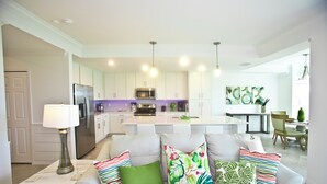 Une cuisine moderne avec des meubles blancs, un îlot central et des luminaires suspendus.