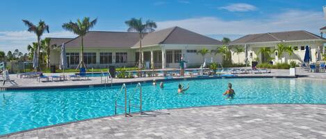 A swimming pool with lounge chairs and palm trees.