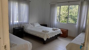 A room with two single beds, a nightstand, a wooden chest, and a window with curtains. - HOTEL CAMPESTRE EL SALITRE (Villeta)