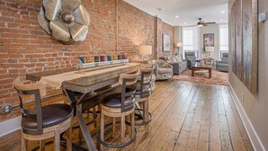 Un'ampia zona giorno con parete in mattoni, un grande fiore decorativo, un tavolo da pranzo in legno con sedie e un angolo relax accogliente.